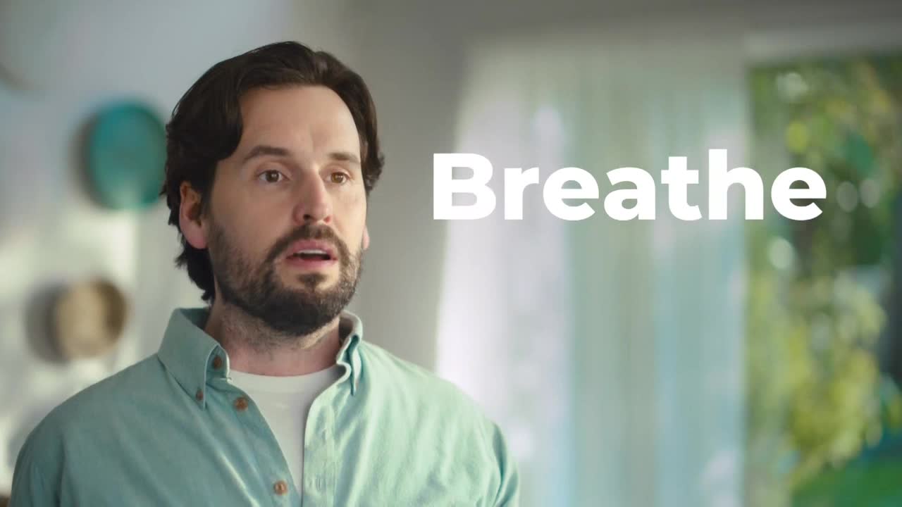 A man with dark hair and a beard stares directly ahead, his mouth slightly open. The word "Breathe" appears in large, white letters beside him.
