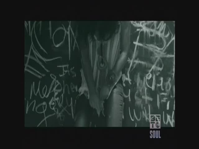 A person in a striped top and leather pants stands in front of a chalkboard covered in chalk writing. The BET Soul logo is in the corner.
