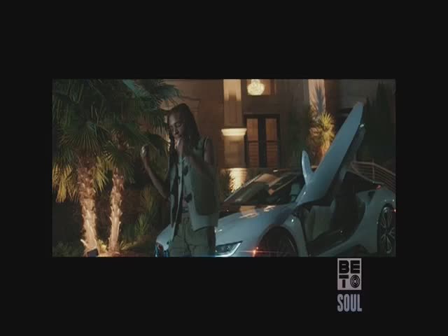 A woman in a vest stands next to a sleek, white sports car with its doors open. The scene is lit by soft outdoor lights, and the BET Soul logo is in the corner.
