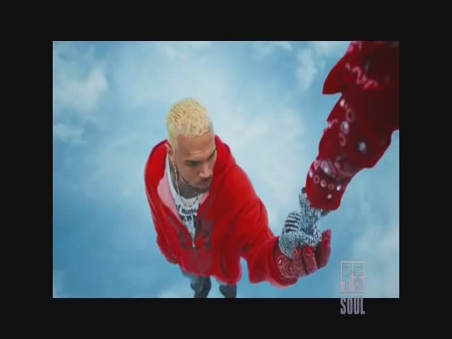 Chris Brown, in a red hoodie, is reaching for a bejeweled hand, both seemingly suspended in the sky. The BET Soul logo sits in the corner.
