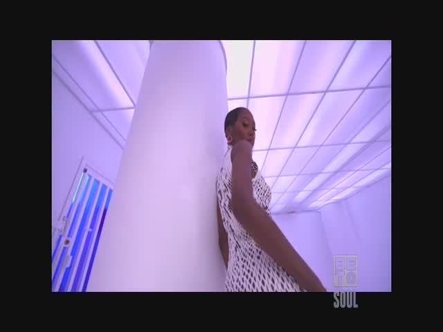 A woman in a white patterned dress leans against a large white pillar, bathed in a cool purple light. The BET Soul logo is visible in the corner.
