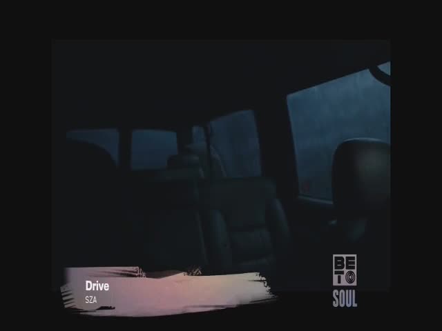 Inside a vehicle, the interior is mostly dark, but the rain-streaked window reveals a stormy, overcast sky. The BET Soul logo and the song title, "Drive" by SZA, appear at the bottom of the screen.

