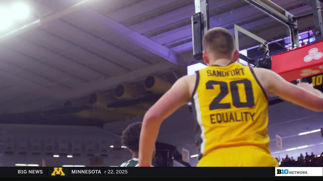 A player wearing number 20 in a yellow jersey is leaping, arms outstretched, near the basket. The Big Ten Network logo is visible in the corner.
