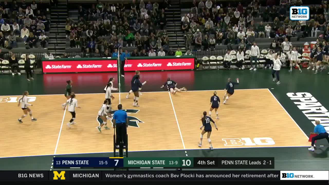 The ball is in the air, heading toward the Penn State side of the court. A Michigan State player dives to the floor, trying to keep the play alive.
