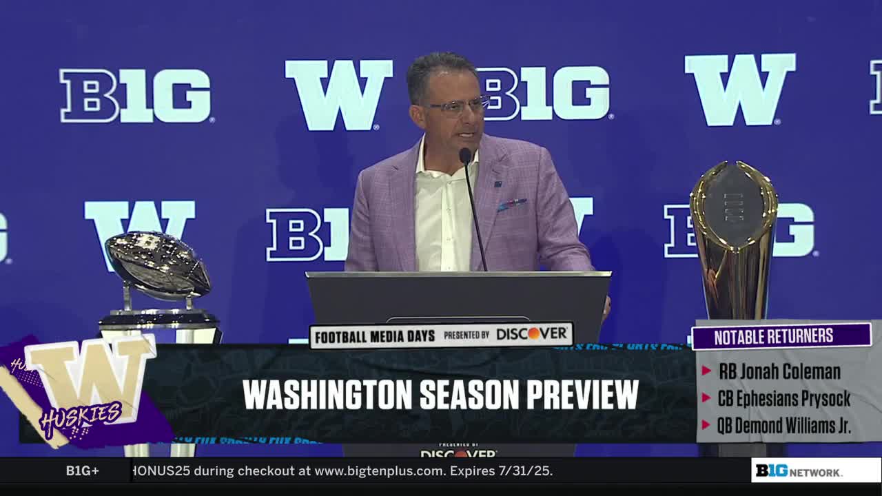 A man in a light purple blazer speaks into a microphone at a podium, with the Big Ten Network logo visible. Behind him, two football trophies and a "Washington Season Preview" graphic are displayed.
