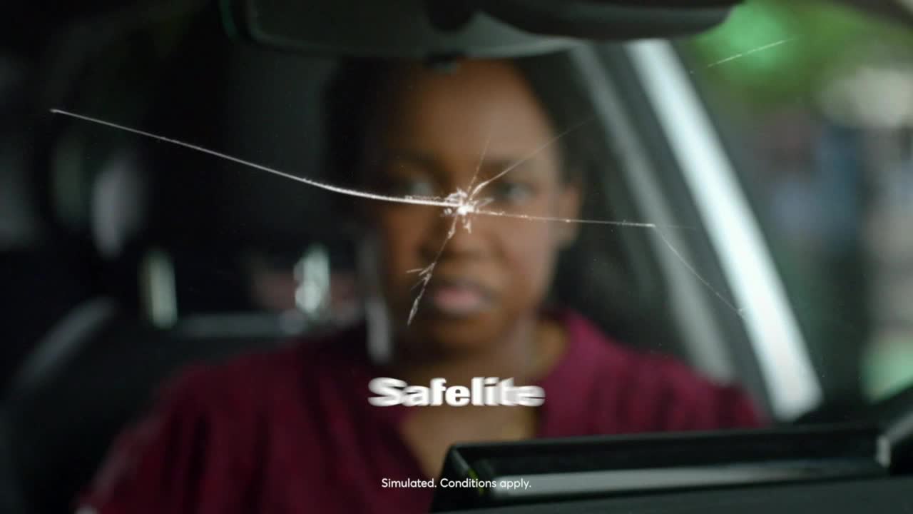 A spiderweb of cracks spreads across the windshield, centered on a point near the driver's eye level. The Safelite logo appears below the damage.
