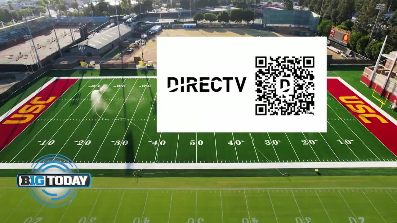 The sprinklers are on, arcing water across the green turf of the USC football field. A DirectTV ad and a Big Ten Network logo are superimposed over the scene.
