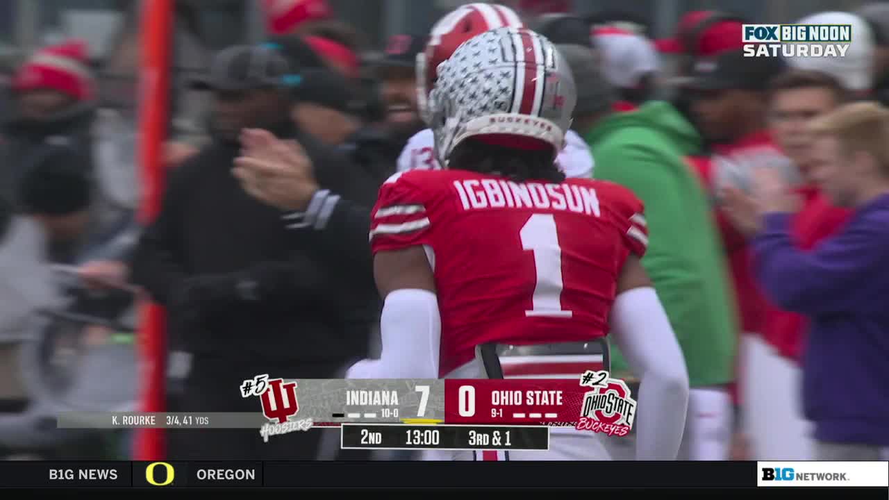 Number one, Igbindosun, is jogging toward the sideline, his helmet with the American flag design reflecting the light. The Ohio State Buckeyes are down seven points, and the clock shows thirteen minutes left in the second quarter.
