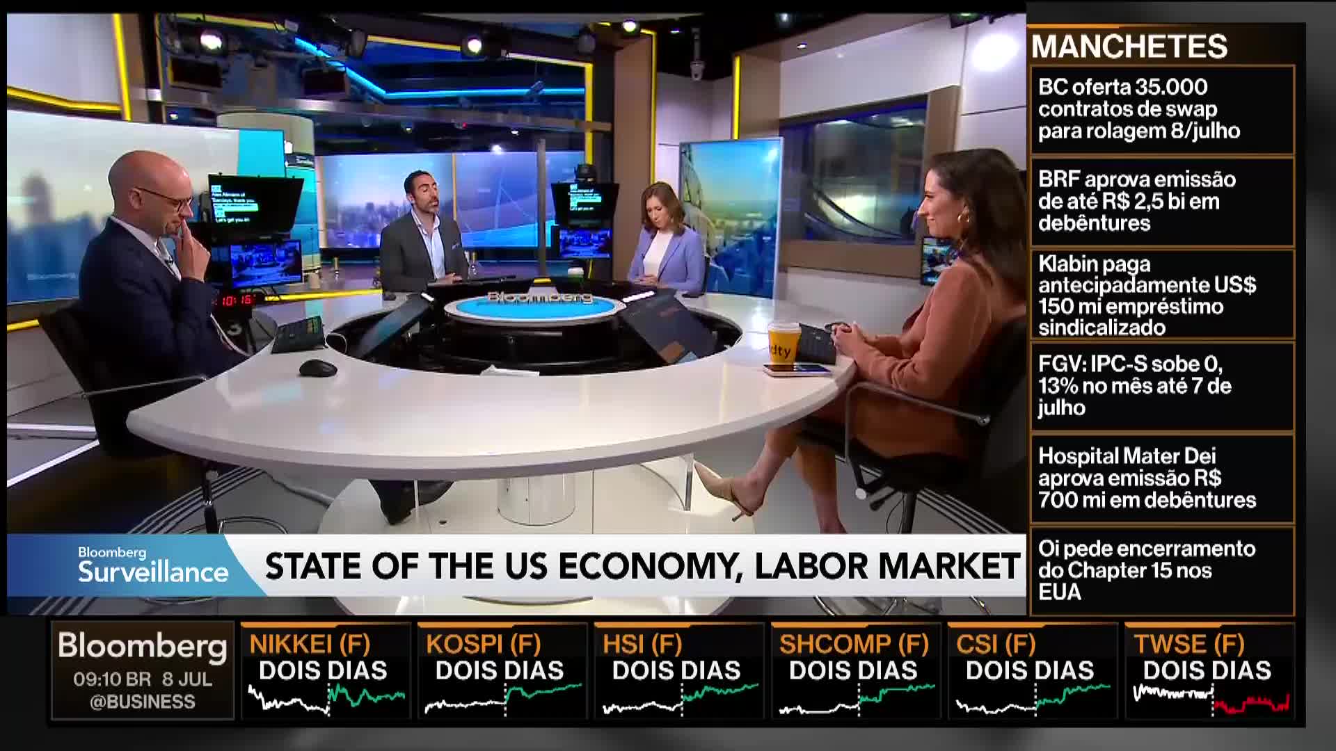 On Bloomberg TV, four people sit around a large, white desk discussing the "State of the US Economy, Labor Market." A woman in a brown jacket gestures while looking at a tablet.
