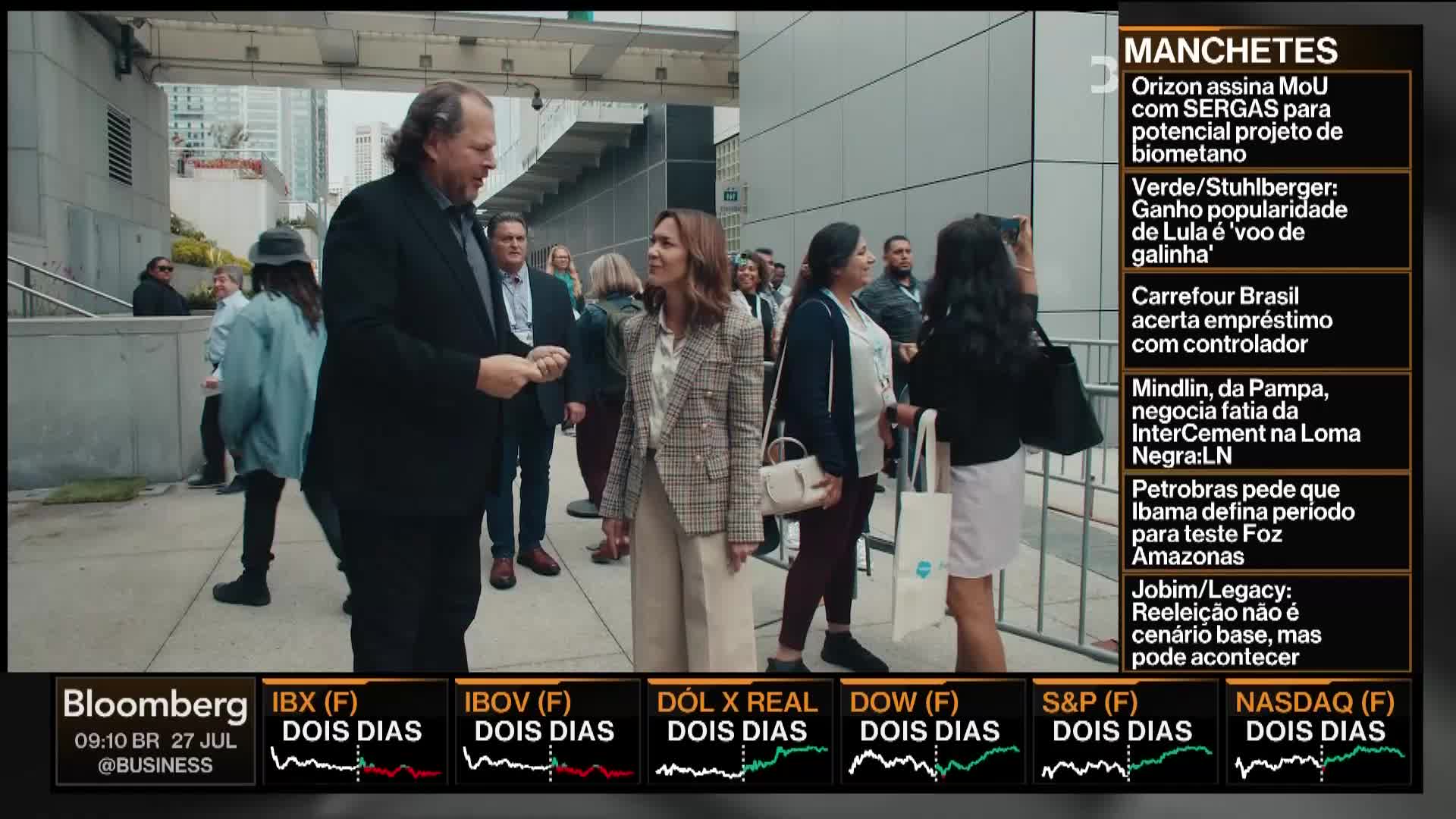 A group of people, some in suits, are gathered outside a building, likely in the United States. A Bloomberg TV graphic in the corner indicates a news broadcast is underway.
