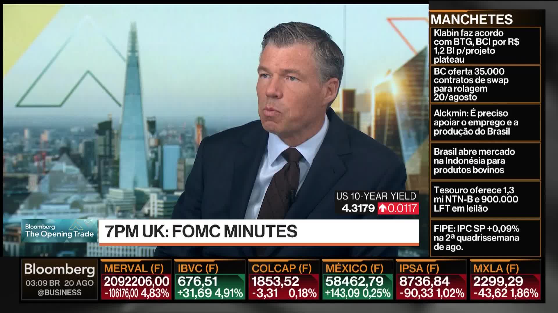 A man in a suit is the focus, speaking on Bloomberg TV. Behind him, a cityscape with a tall, pointed building is visible.
