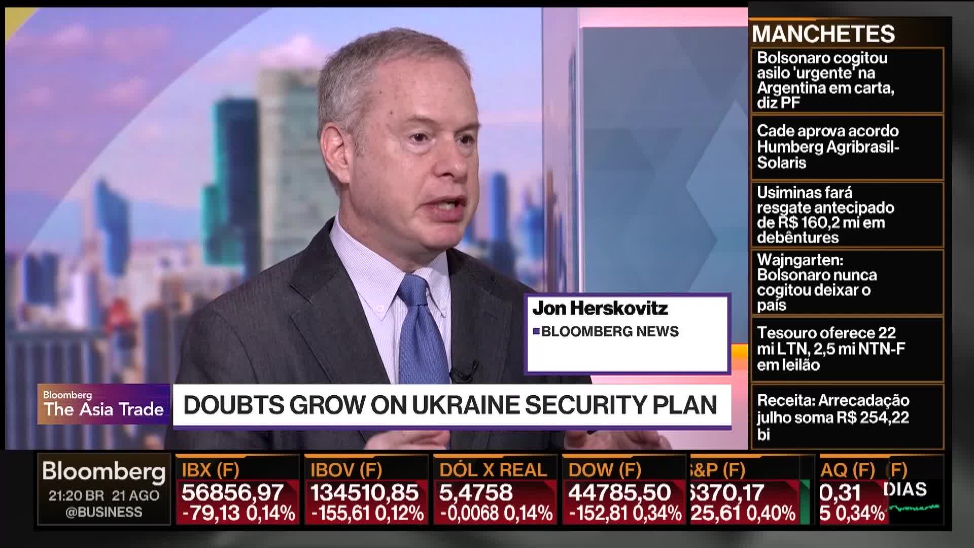 A man in a suit and tie speaks directly to the camera on Bloomberg News, his mouth open as he delivers a report. Below him, a graphic announces "DOUBTS GROW ON UKRAINE SECURITY PLAN."
