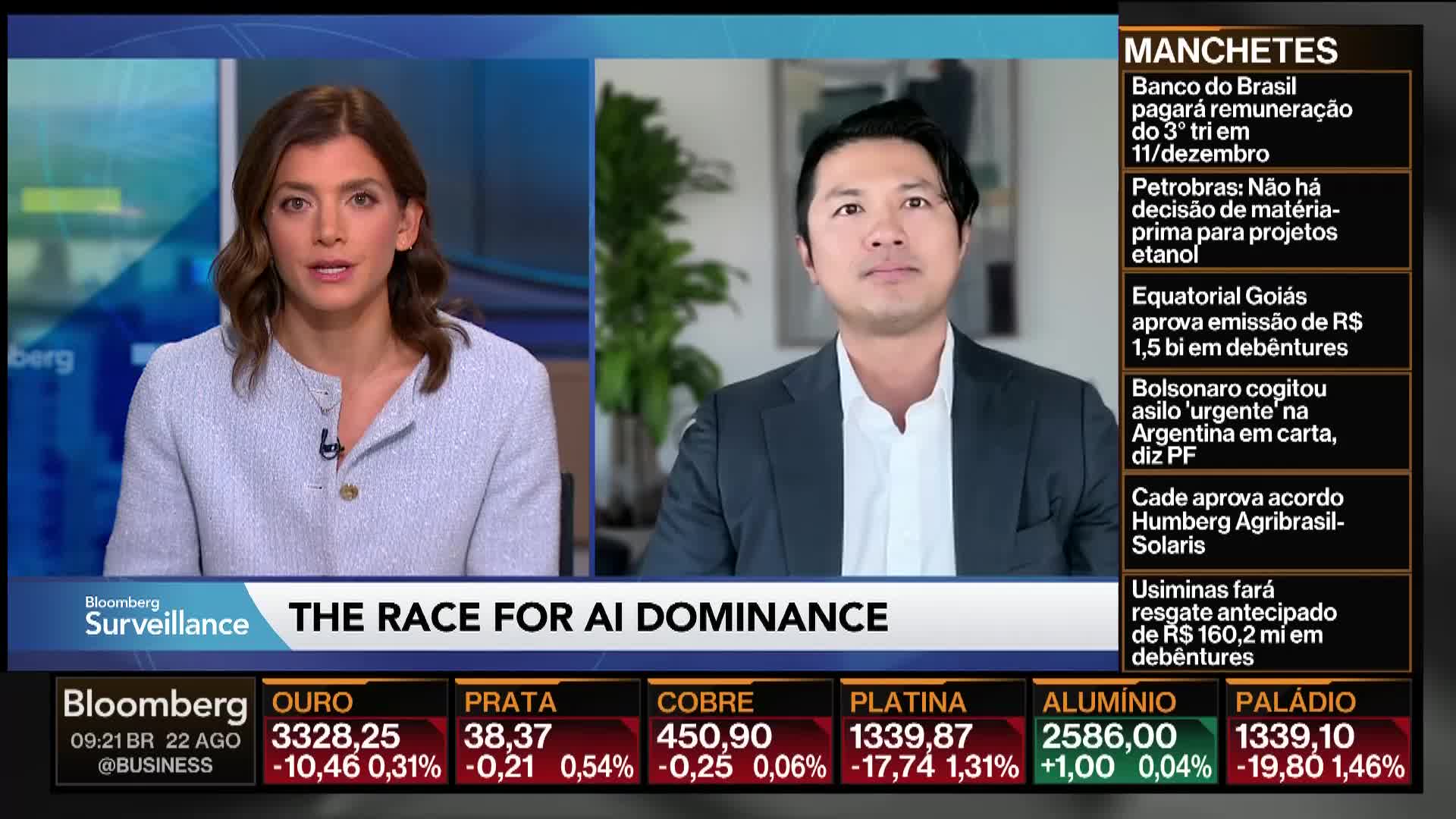 On Bloomberg TV, a woman and a man are each framed on screen, both looking directly at the camera. The chyron reads "THE RACE FOR AI DOMINANCE" as financial data scrolls at the bottom.
