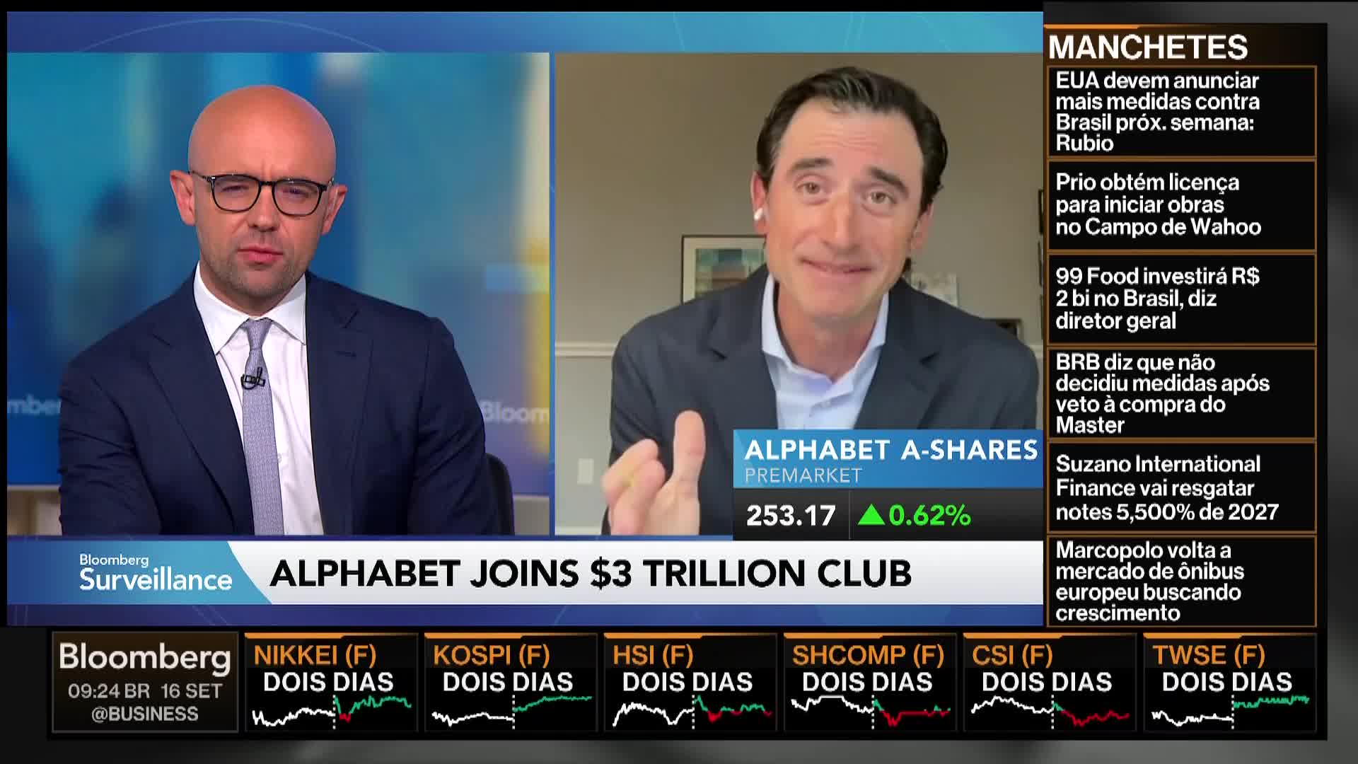 Two men, both in suits, are speaking on Bloomberg TV. The man on the right gestures with his hands as he talks, while the other listens intently.
