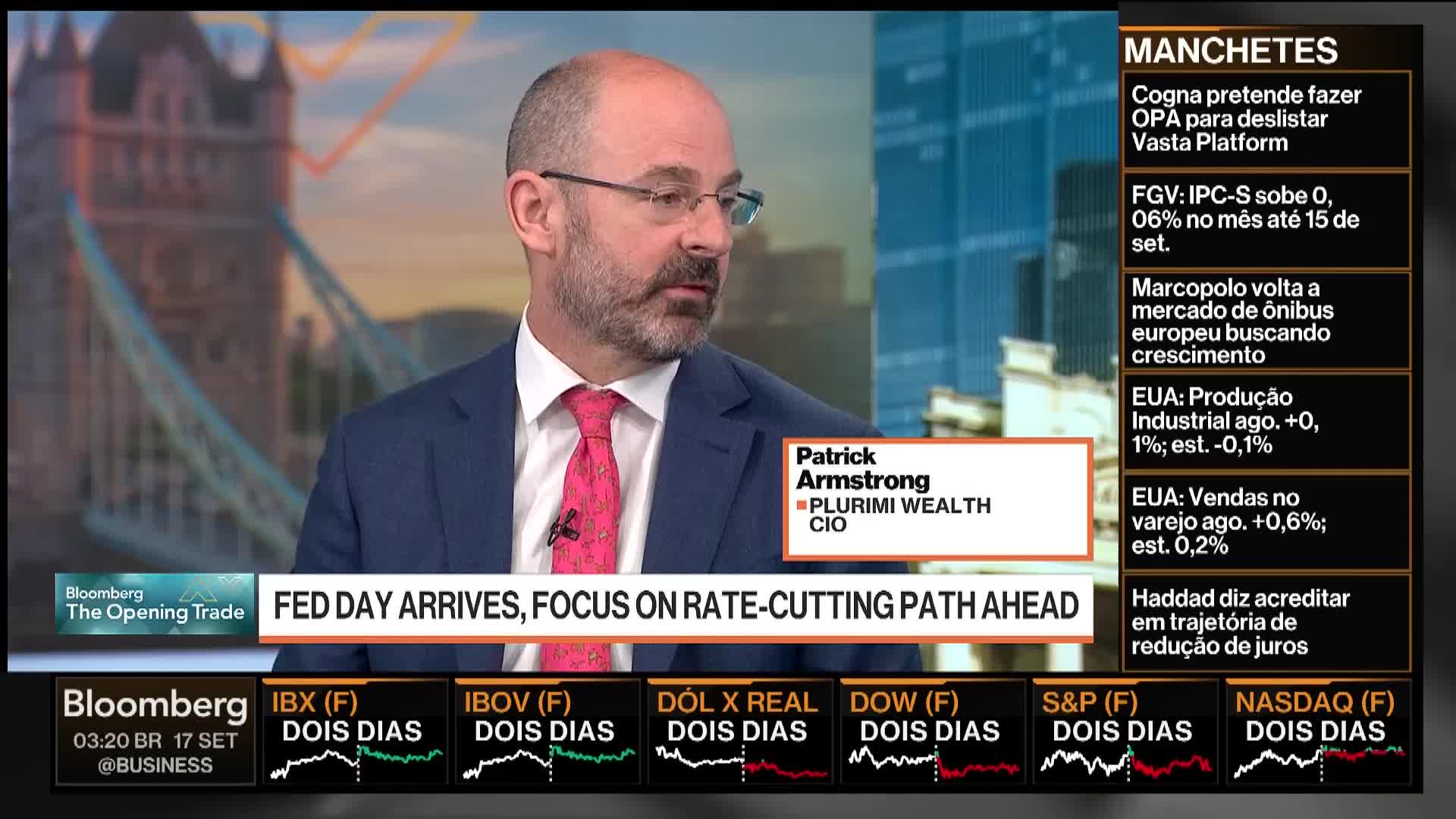 A man in a suit and tie is speaking, his image framed by a Bloomberg TV graphic. Below, stock market data and headlines scroll across the screen.
