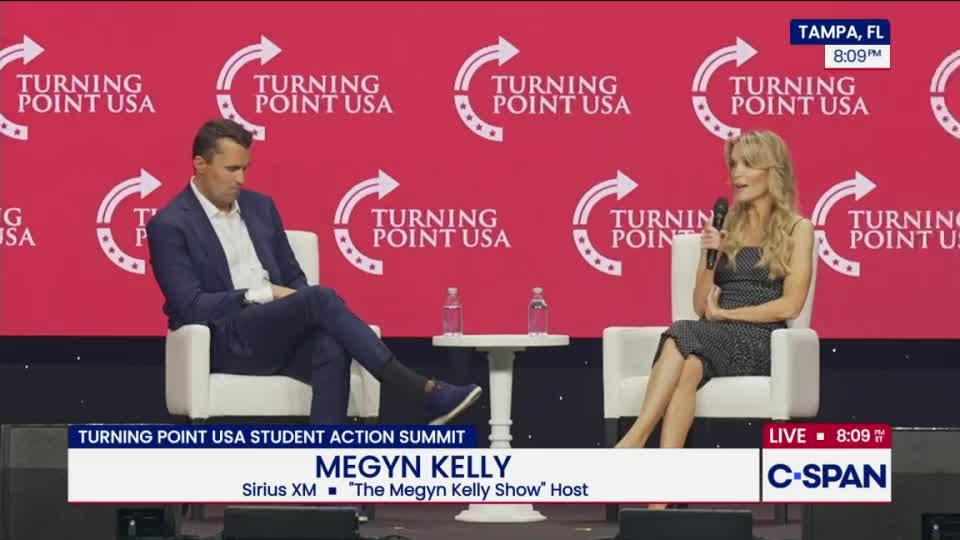 Megyn Kelly, holding a microphone, is speaking on a stage with a "Turning Point USA" backdrop, and a man in a suit is seated beside her. The C-SPAN logo is in the bottom right corner, indicating a live broadcast from Tampa, Florida.
