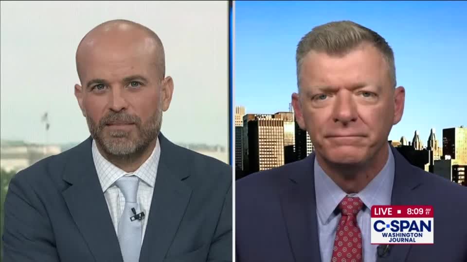 Two men in suits are on a C-SPAN broadcast, each framed in separate panels. One man is in front of a window, while the other is set against a city skyline, the C-SPAN logo visible in the corner.

