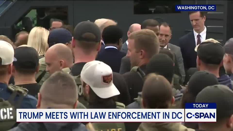 A crowd of people, many wearing baseball caps, are gathered together, with a few in suits visible in the middle. The C-SPAN banner at the bottom of the screen indicates the event is taking place in Washington, D.C.
