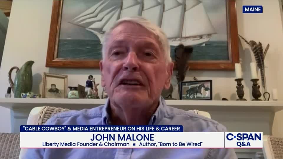 John Malone, identified on C-SPAN as a media entrepreneur, is speaking directly into the camera. The lower third of the screen displays his name and credentials, while a "MAINE" graphic appears in the upper right.

