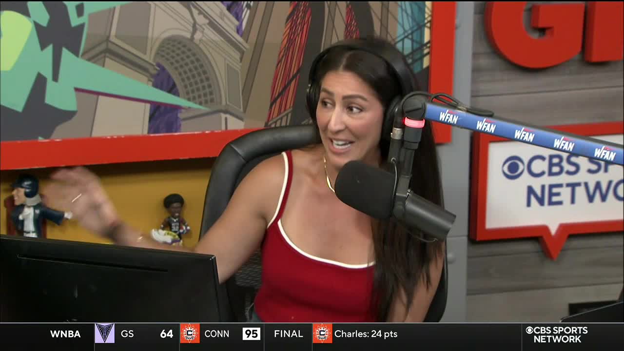 A woman in a red tank top gestures with her left hand while speaking into a microphone. The CBS Sports Network logo is visible on the right, and the WFAN logo is on the microphone boom.
