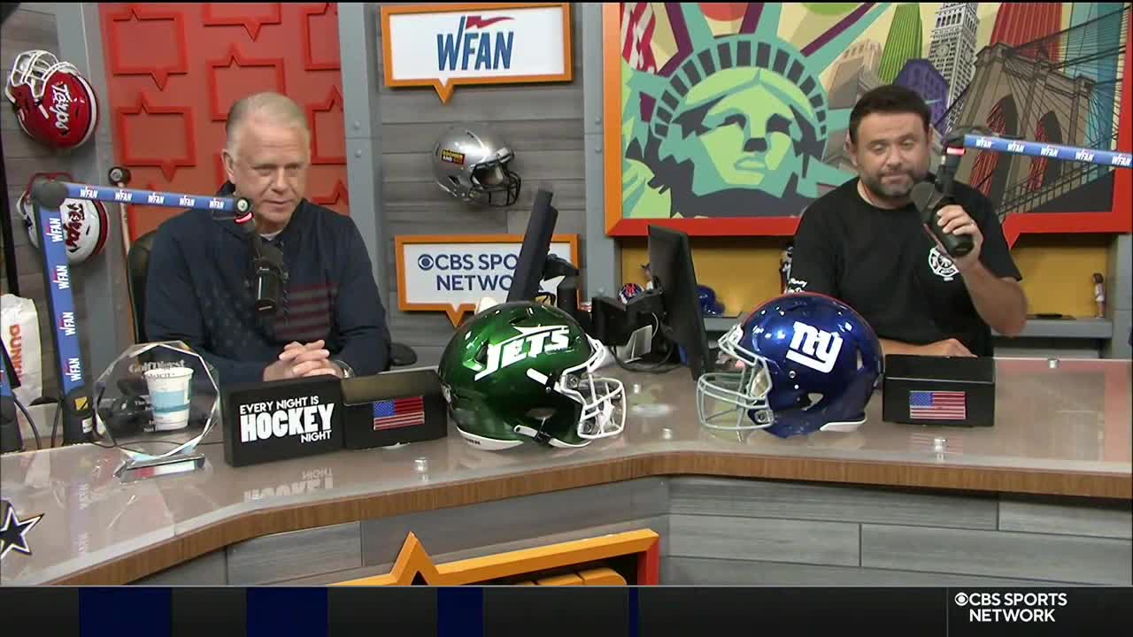 Two men sit at a desk, each with a microphone in front of them. Between them sit a New York Jets helmet and a New York Giants helmet, with the CBS Sports Network logo visible.
