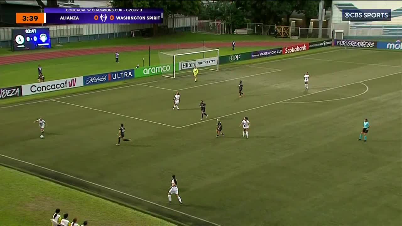 A player in white dribbles the ball upfield, while several teammates and opponents in black and white jerseys position themselves. The score is tied, as the Washington Spirit and Alianza face off on CBS Sports Network USA.
