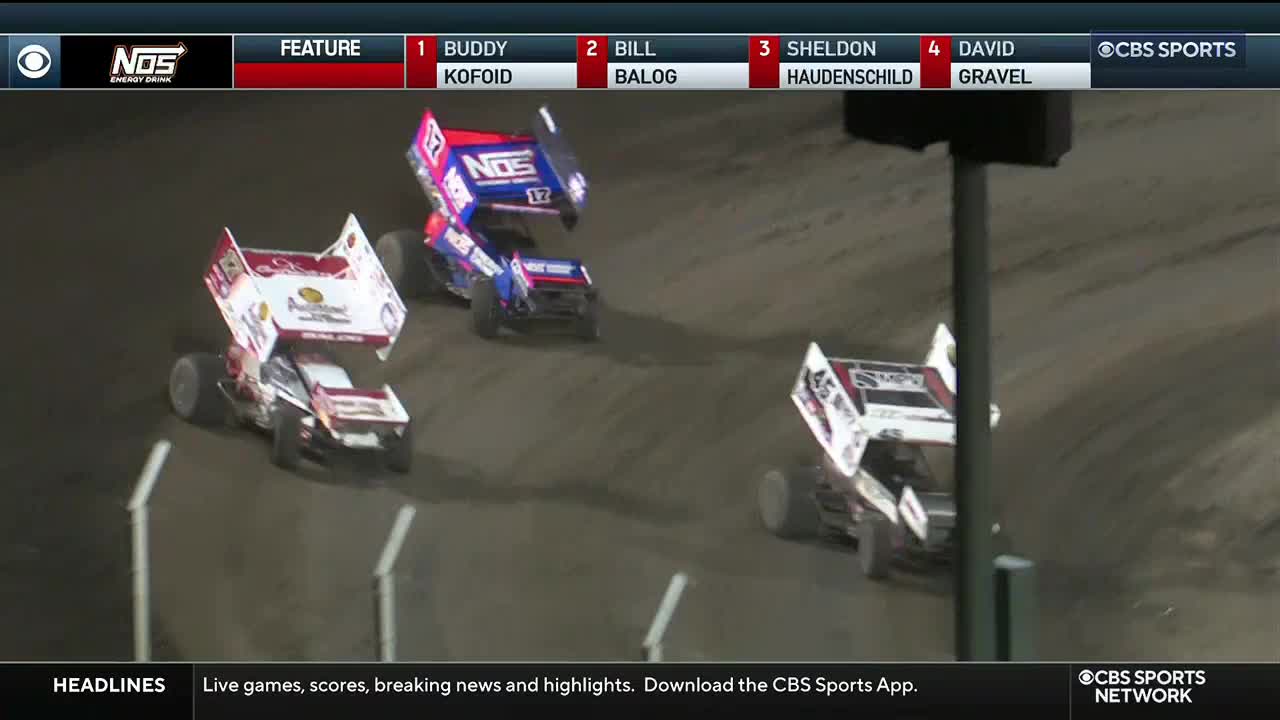 Three sprint cars, each with a tall wing, are kicking up dirt as they navigate the track. The broadcast on CBS Sports Network USA shows the race's Feature with Buddy Kofoid leading the pack.
