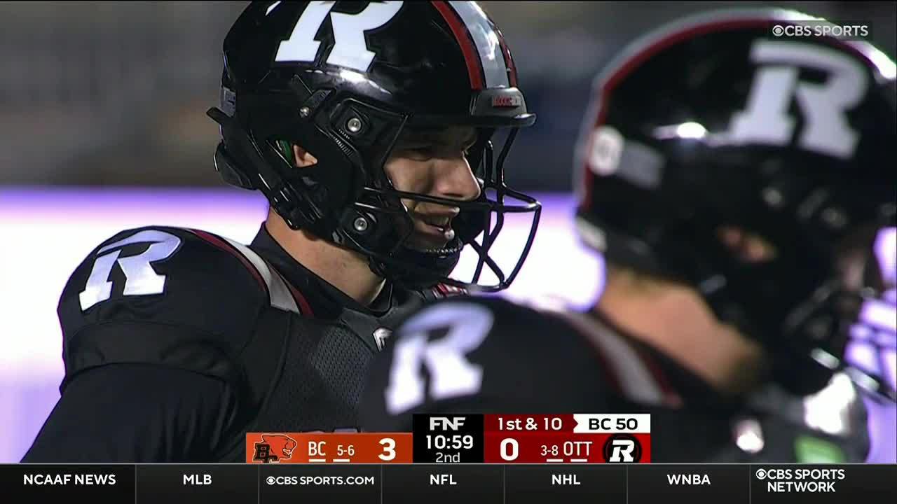 A player in a black helmet and jersey, with a large "R" on his shoulder, is looking towards the sideline. The CBS Sports Network USA broadcast shows the score and the game clock.
