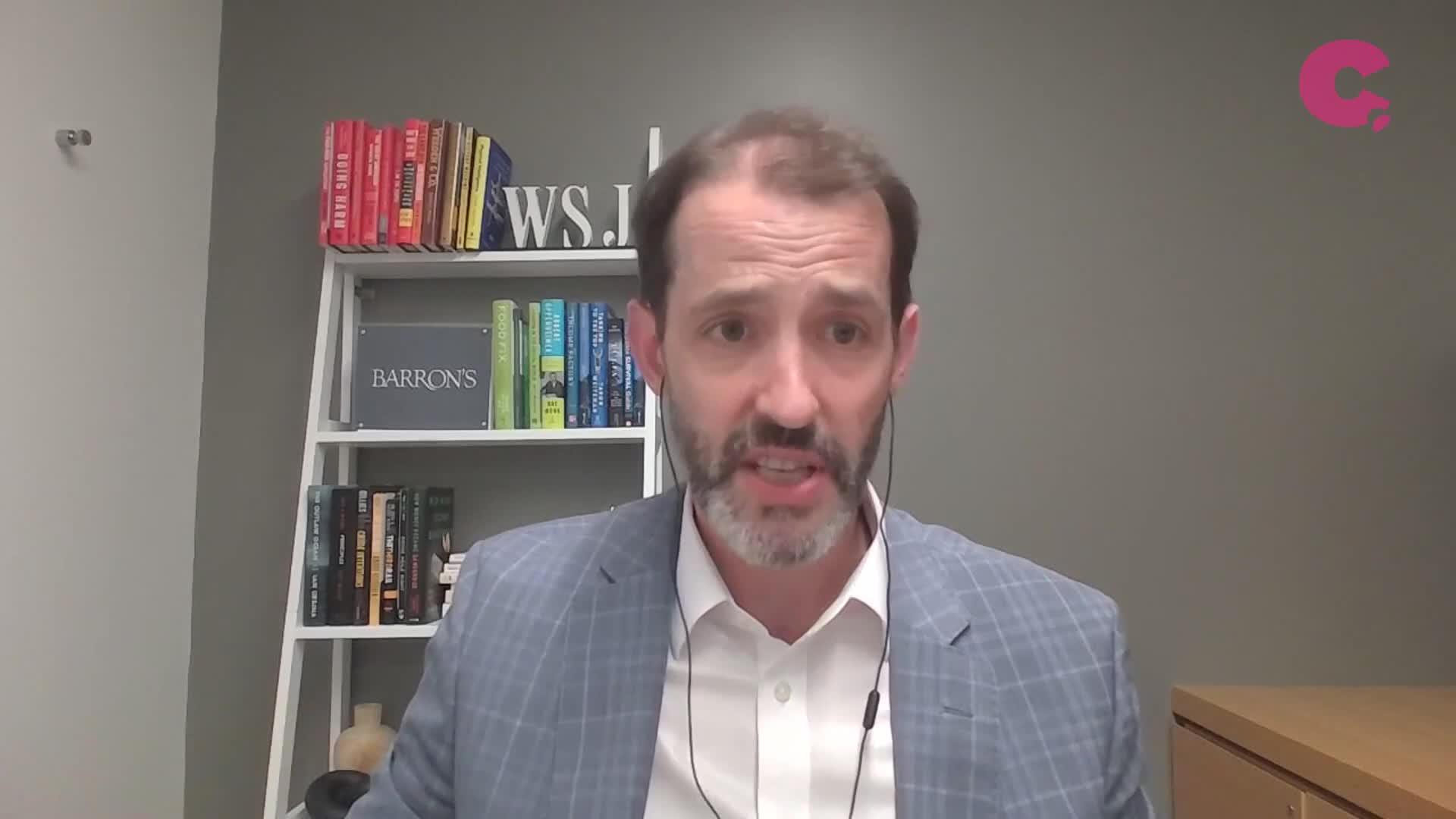 A man with a beard and a checked blazer is speaking, his mouth moving as he talks. He's wearing a headset and the Cheddar News logo is visible in the corner.

