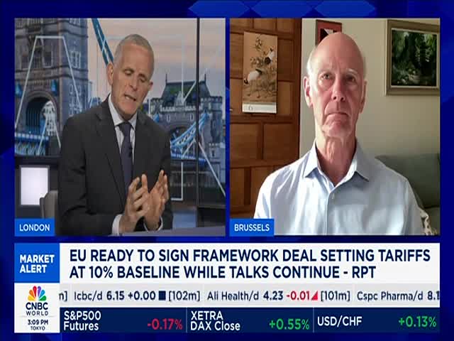 A man in a suit gestures with his hands while speaking, a backdrop of London behind him. Across the screen, another man in a button-down shirt listens from Brussels, both appearing on CNBC World.
