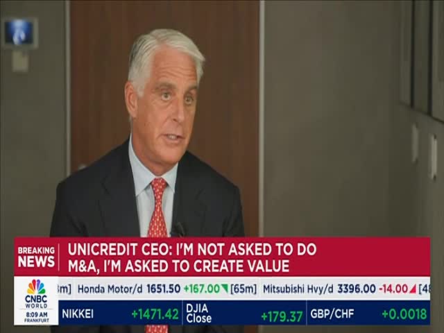 The Unicredit CEO, in a suit and tie, is speaking directly to the camera, his expression serious. A CNBC World graphic at the bottom of the screen displays stock market data and the headline "Unicredit CEO: I'm not asked to do M&A, I'm asked to create value."
