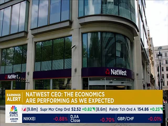 The NatWest building, with its reflective windows, stands prominently on a city street. A CNBC World graphic displays financial news, including a headline about the bank's CEO.
