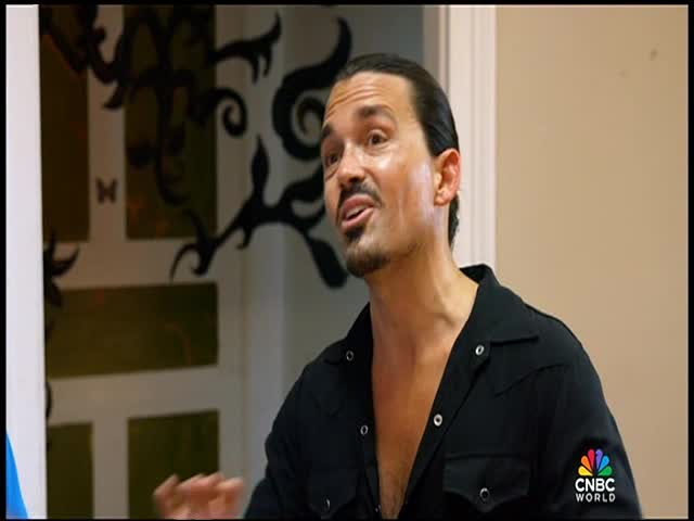 The man is speaking, his mouth open as he gestures with his hands just off-camera. A CNBC World logo is visible on his left sleeve.
