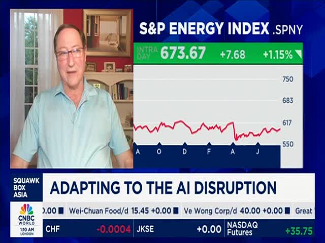 A man in a light blue shirt is speaking on CNBC World, with a stock market graph displayed behind him. The screen shows the S&P Energy Index and a headline about adapting to AI disruption.
