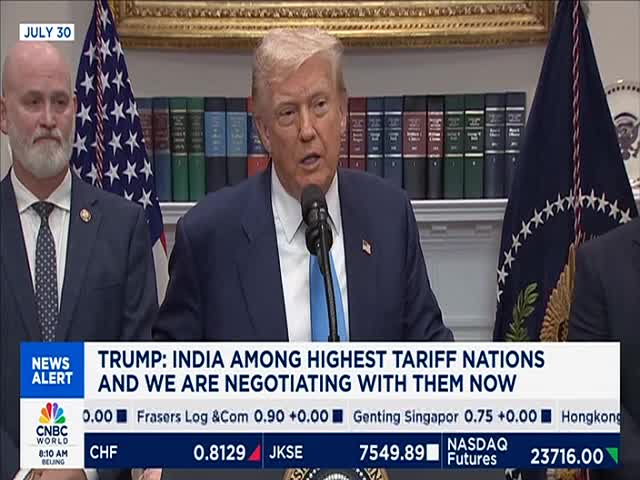 The former President is speaking into a microphone, his face animated. Behind him, the American flag and a CNBC World news ticker are visible.
