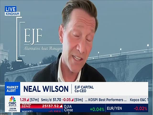 A man, identified as Neal Wilson on CNBC World, is speaking, with a background of a bridge and a cityscape. The lower third of the screen displays financial data and market alerts.
