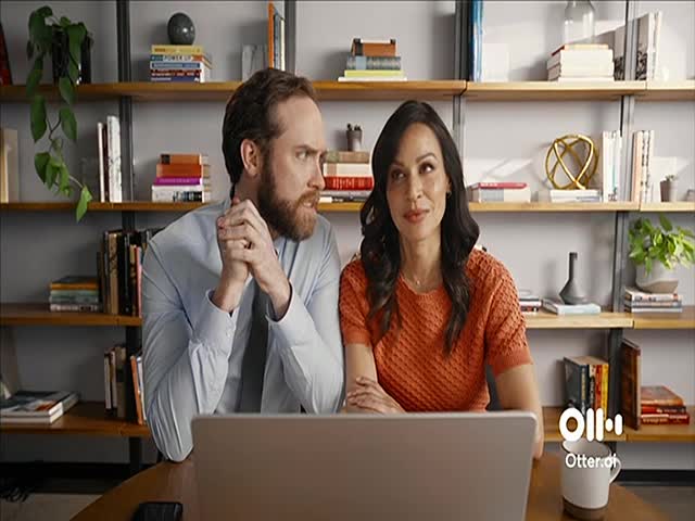 A man and a woman sit close together, looking at a laptop. The woman is smiling, while the man's expression is more thoughtful.
