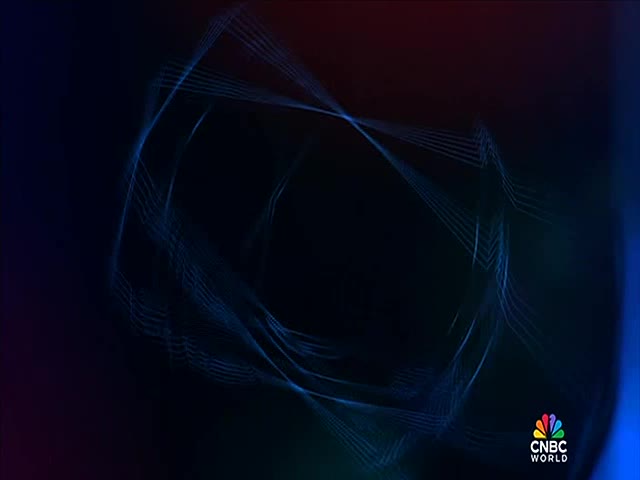 Thin, blue lines weave across the screen, forming a geometric pattern against a dark background. The CNBC World logo sits in the lower right corner.
