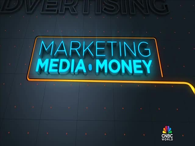 "MARKETING MEDIA MONEY" glows in bright blue neon, framed by a yellow-orange outline. The CNBC World logo sits in the lower right corner.

