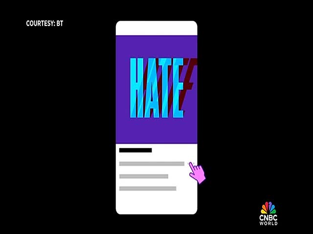 A phone screen displays the word "HATE" in bold, blue letters, with a pink cursor hovering over a list of text. The CNBC World logo is visible in the corner.
