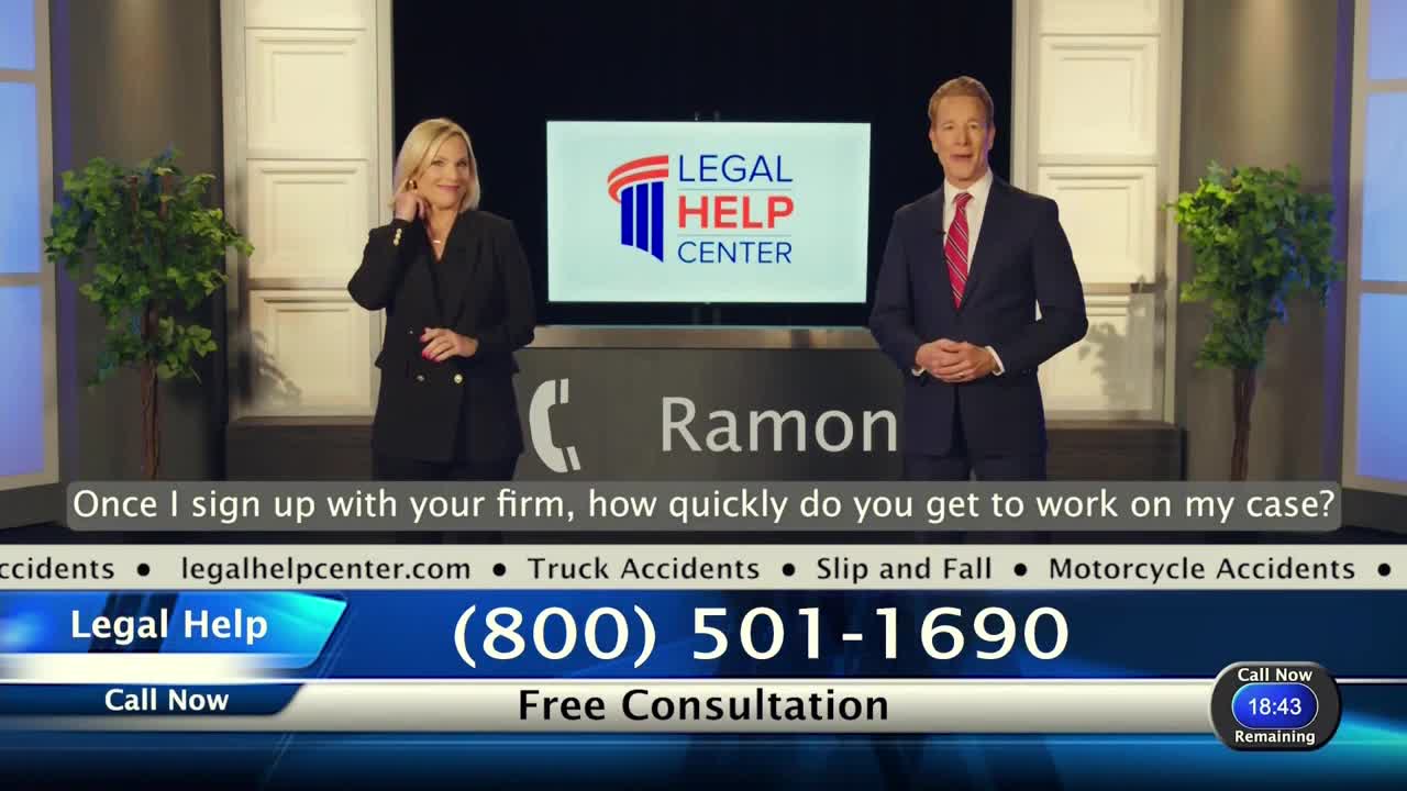 A man and woman in suits stand in front of a "Legal Help Center" backdrop, likely a commercial. The woman is touching her ear, and the man is smiling, ready to answer a question.
