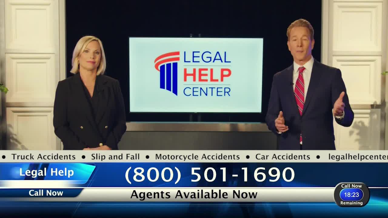 A man in a suit gestures with his hands, while a woman beside him stands still.  Behind them, a screen displays the "Legal Help Center" logo and a phone number.
