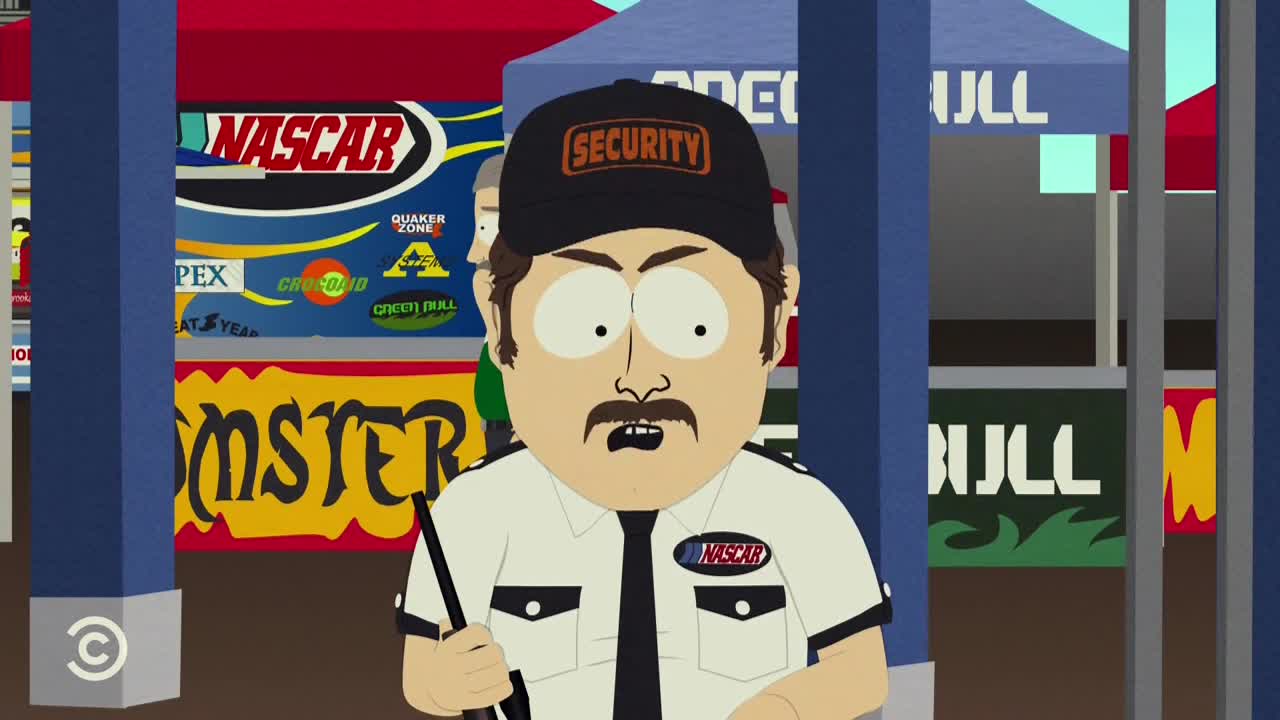 A security guard, wearing a black hat and a stern expression, holds a baton, standing in front of a NASCAR banner. The Comedy Central logo is visible on the bottom left.
