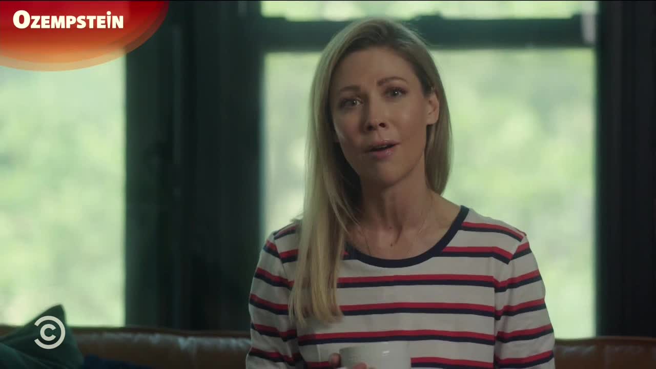 A woman with blonde hair and a striped shirt speaks directly to the camera, holding a white mug. The Comedy Central logo is visible in the corner, and a graphic reads "Ozempstein" at the top.
