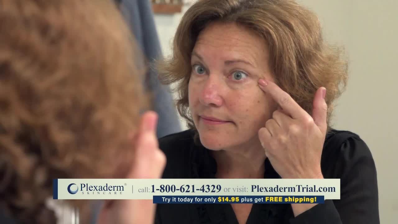A woman in a black shirt is staring intently at her reflection, her finger pointing at the skin around her eye. The bottom of the screen displays an advertisement for a skincare product.
