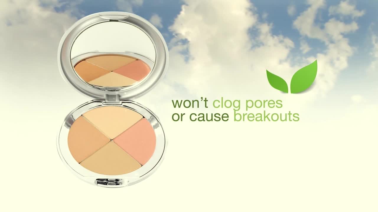 An open compact of face powder sits, reflecting the sky in its mirror. The product's claim, "won't clog pores or cause breakouts," is displayed next to a pair of green leaves.
