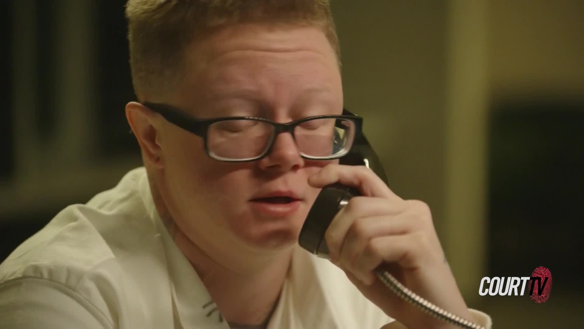 A man in glasses holds a black telephone receiver to his ear, speaking. The Court TV logo is visible in the corner, indicating this is likely a scene from a legal proceeding in the United States.
