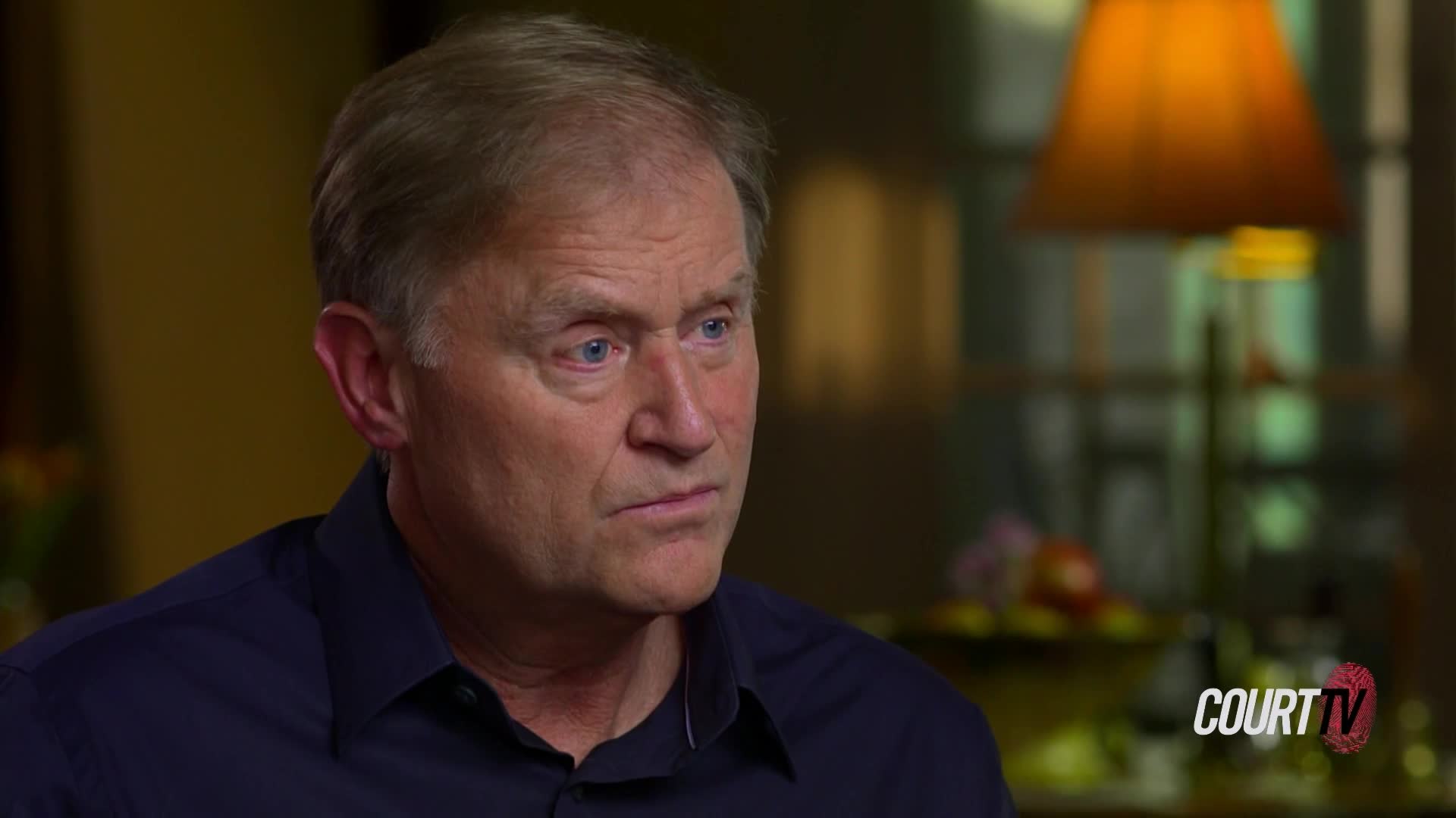 A man with blue eyes stares intently, his face illuminated by a soft light. The Court TV logo is visible in the corner, suggesting an interview setting.
