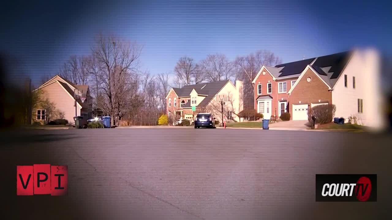 A dark blue SUV slowly backs out of a driveway. The houses lining the street are typical of a suburban neighborhood in the United States.