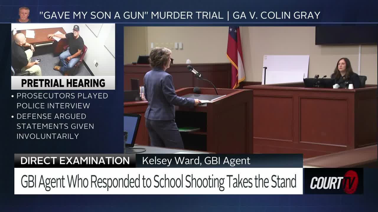 A woman in a dark suit stands at a podium, facing away from me. Another woman, also in dark clothing, sits behind a wooden desk to the right. The courtroom is set up for a trial, with the Georgia flag visible behind the seated woman.